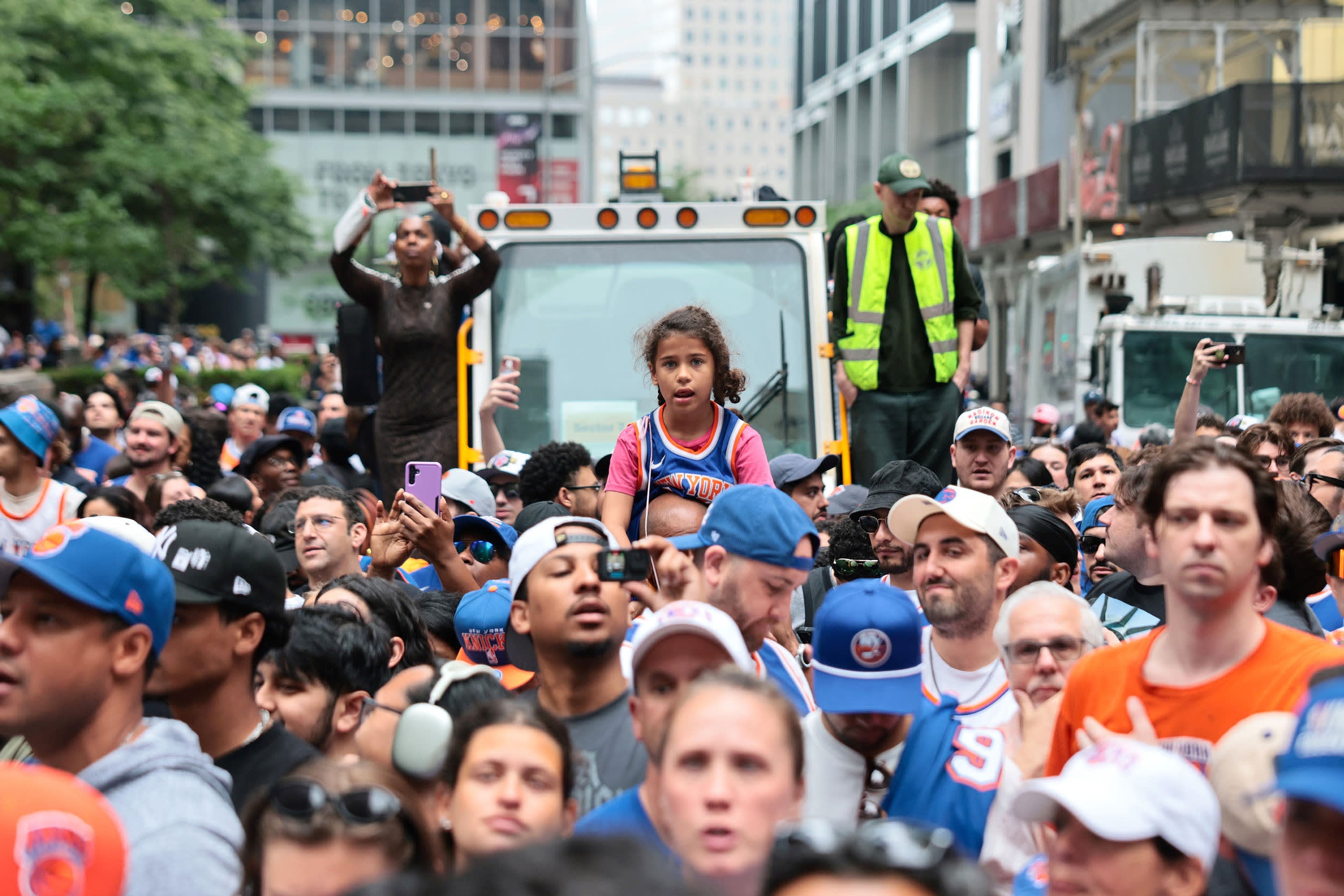Crowd of people in a city street with a construction vehicle in the background