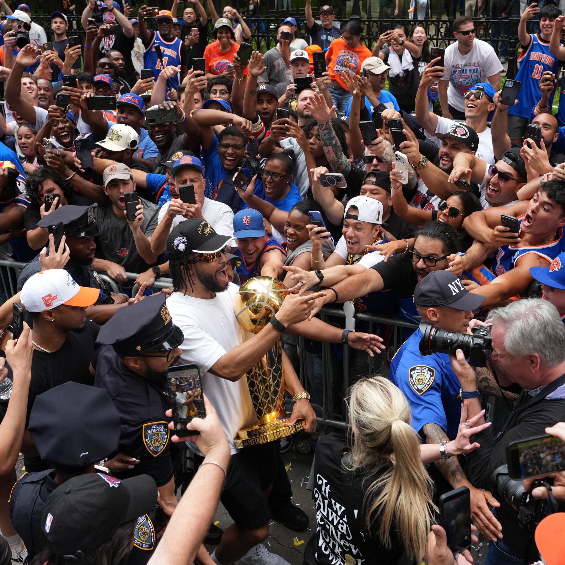 Man in gold boxing glove interacting with a crowd of people, including police officers and media personnel.