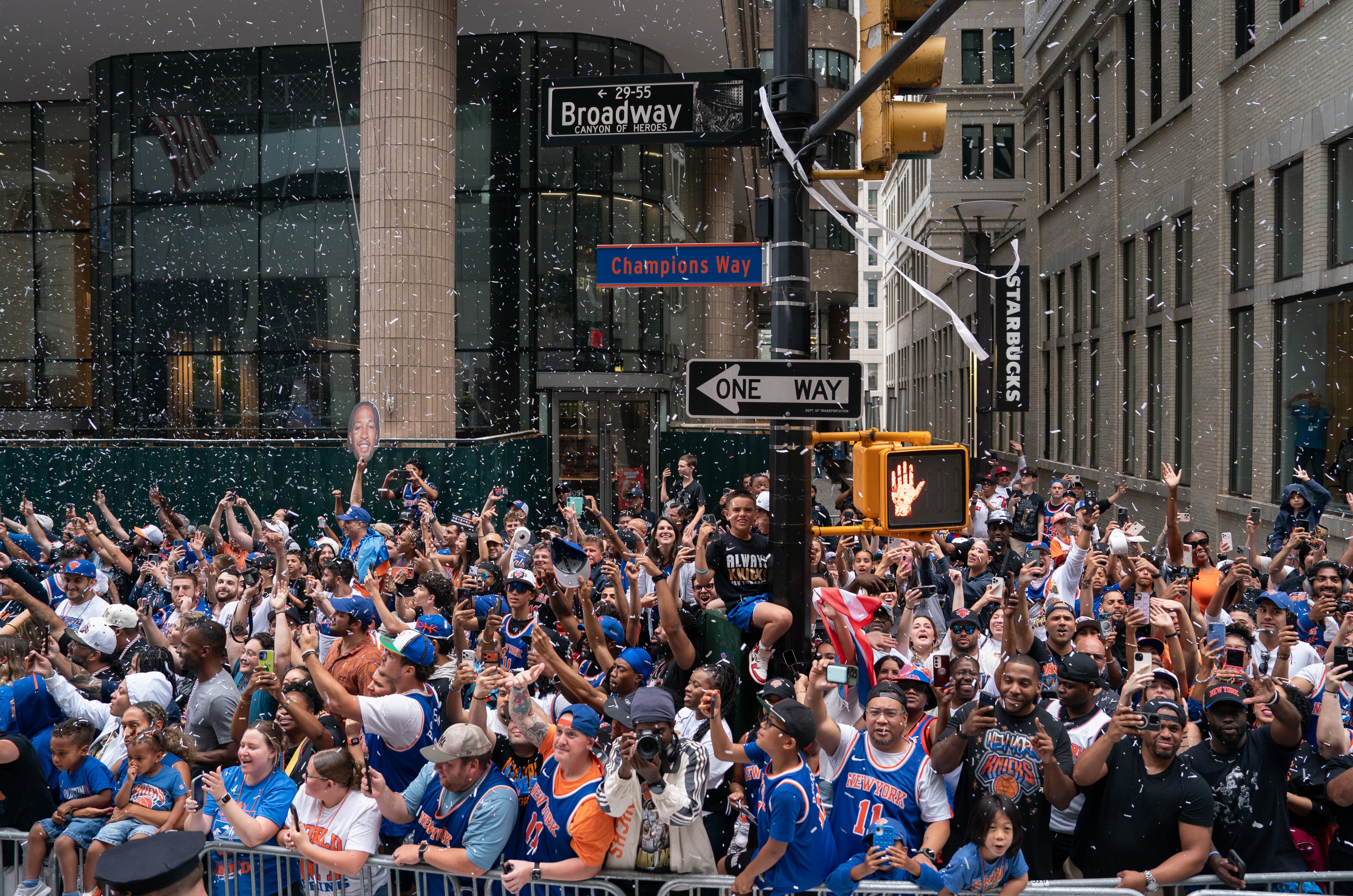 Crowd of people in a city street with snow falling, celebrating an event.