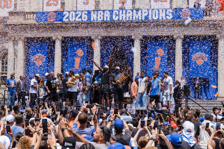 Celebration of the 2026 NBA Champions with confetti and a large banner on a building facade.