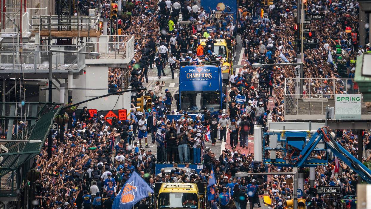 Large crowd of people at a sports event with a prominent blue banner and flags.