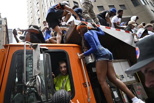 People climbing onto an orange truck in a city street